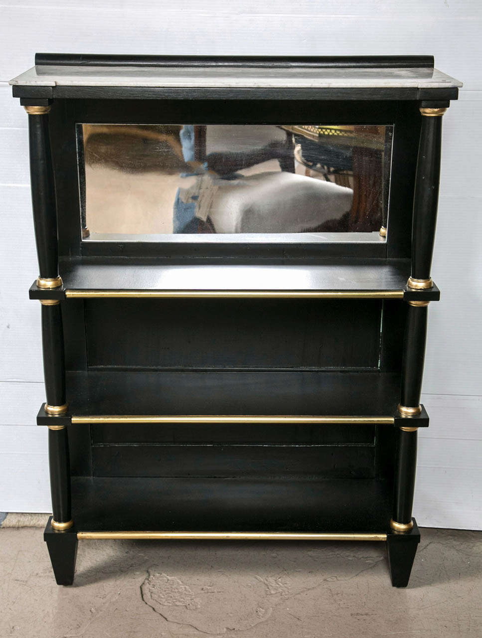 A pair of Marble top Bookcase cabinets or shelving units by Maison Jansen. Each ebonized and gilt gold hi lighted cabinet with a square tapering leg leading to a set of four shelves all flanked by circular columns. The upper shelving area with a