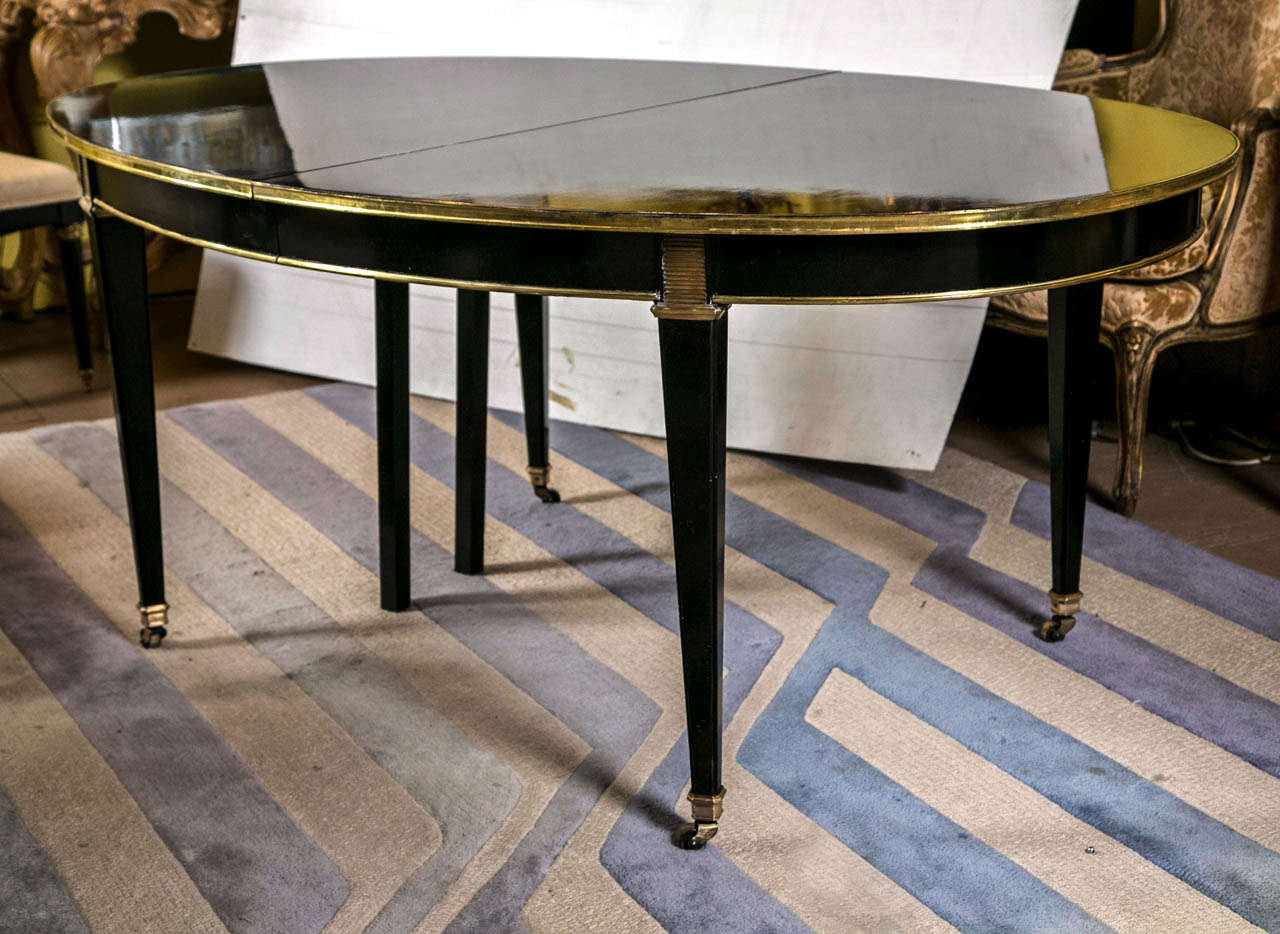 A finely polished ebonized dinning table by Maison Jansen. This table with 3 Leaves measuring 18