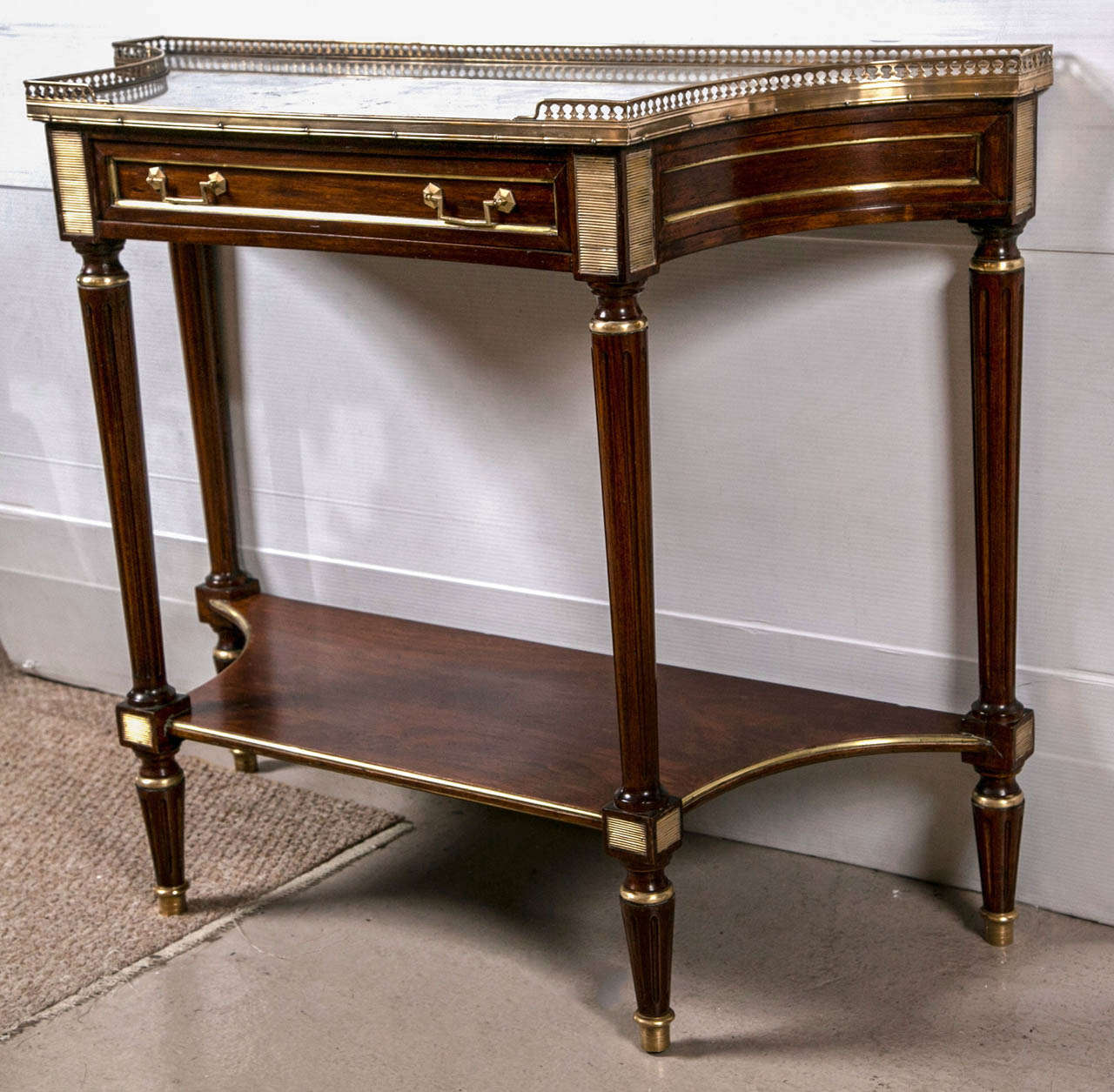 Louis XVI  Style Console / Deserte Marble Top Stand by Jansen. A fine Louis XVI style console with inverted sides framed in bronze borders. The bronze sabot feet leading to a group of cookie cutter bronze corners having a lower shelf. The single