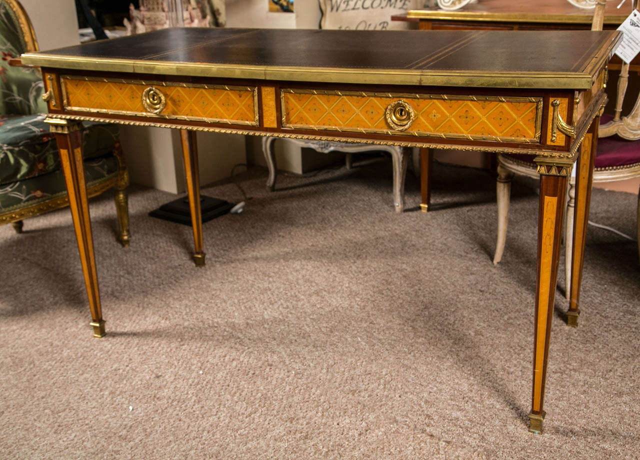 A finely bronze mounted desk by Maison Jansen. The overall casing with oak secondary woods finely inlaid. Having bronze sabots leading to tapering legs with satinwood and mahogany inlays terminating in bronze caps. This three drawer desk is finely