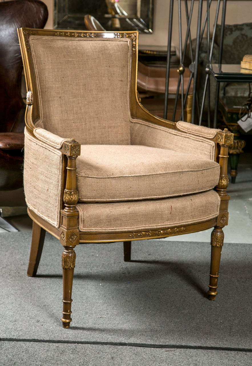 Pair of Louis XVI Style Maison Jansen Bergeres. The turned and carved feet leading to a newly upholstered burlap Bergere chair. The arms with turned spindle supports terminating in square tops and arm rests. As seen in the Jansen furniture books