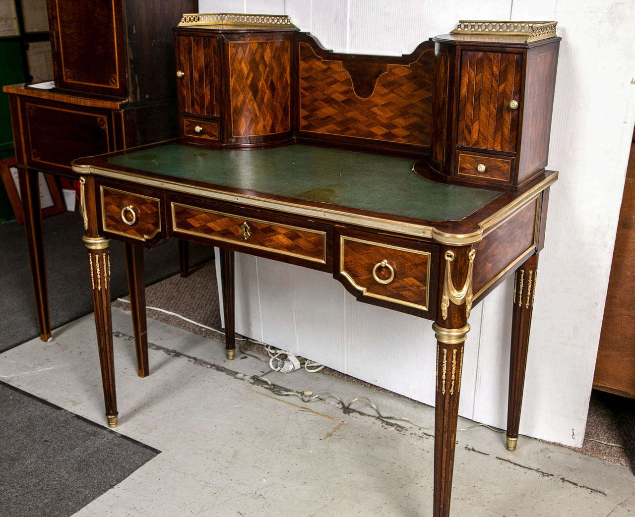 A wonderfully cast bronze mounted desk in the manner of F. Linke. The Louis XVI style legs all bronze mounted leading to a knee hole desk with all over parquetry design. The bronze framed top having a leather tooled writting surface. The top with a