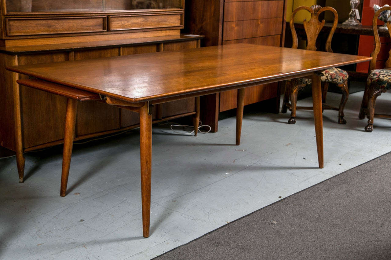 A fine Hans Wegner Design Mid-Century Modern Teak-wood Dining Table.
The top with pull out leaves on splayed cylindracil legs. The table branded under the table top.