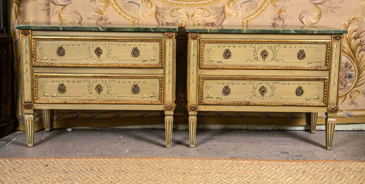 A pair of finely constructed two drawer bachelor chests. Each with a faux marble top supported by a pair of drawers on tapering legs. Both Marked Julia Gray New York. The overall casing having paint decorated leaf and vine on the front as well as