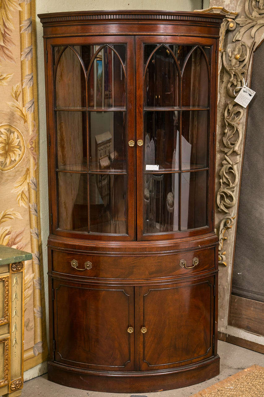 A fine pair of Georgian Style Demi Lune Corner Cabinets by the Fancher Furniture company. Each cabinet with double demi lune doors leading to a single drawer and a pair of lattice worked demi lune glass doors. Fine dental work moldings as well as
