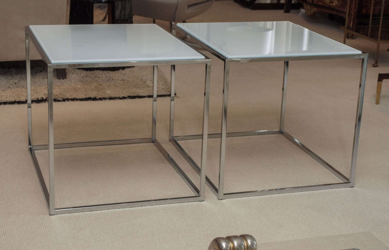 Two elegant and minimal side tables in polished chrome with inset white glass plateaux