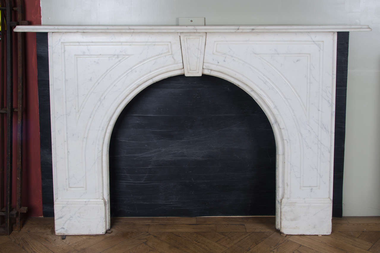 An original Victorian fireplace surround with an arched opening. This antique Carrara marble surround has a traditional Victorian design with an arched opening, a central keystone, and fluted panelling framing the spandrels.