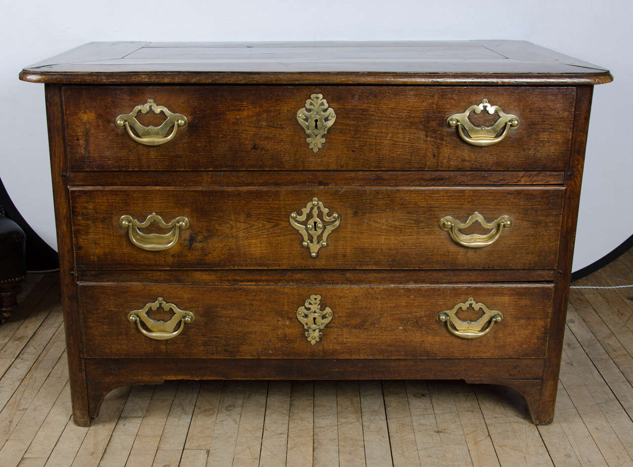 This very handsome and solid 18th century Italian oak commode features the original brass fittings and a magnificent patina plank top. The chest has three long, deep drawers and stands on bracket feet. It measures 47 ¾ in–121.3 cm wide, 24 ¾ in–63