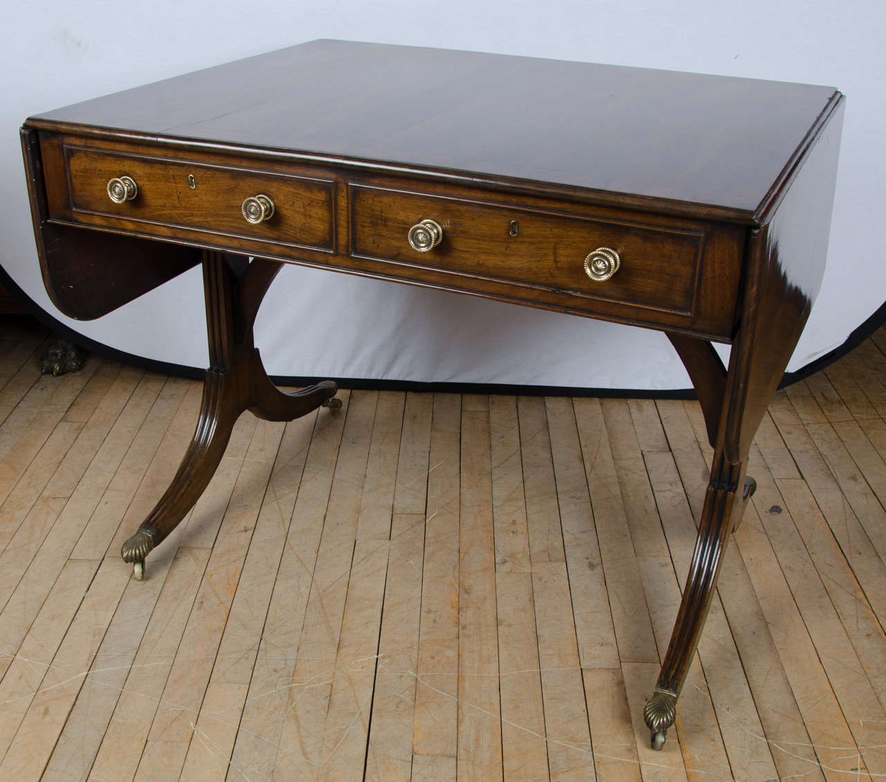 A fine quality 19th C. beautifully paginated mahogany top with a wide rosewood cross banded border that is supported on reeded, Sabre leg end supports with brass castors. The sofa table has 2 top drawers on one side with 2 matching false drawers