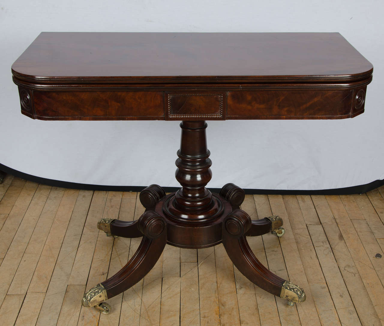 This late Regency mahogany tea table has 4 sweeping legs from a central circular turned column support and is finished with finely cast brass feet.  The table features a lovely patina top, both inside and out. It measures 36 in – 91 cm wide and 29