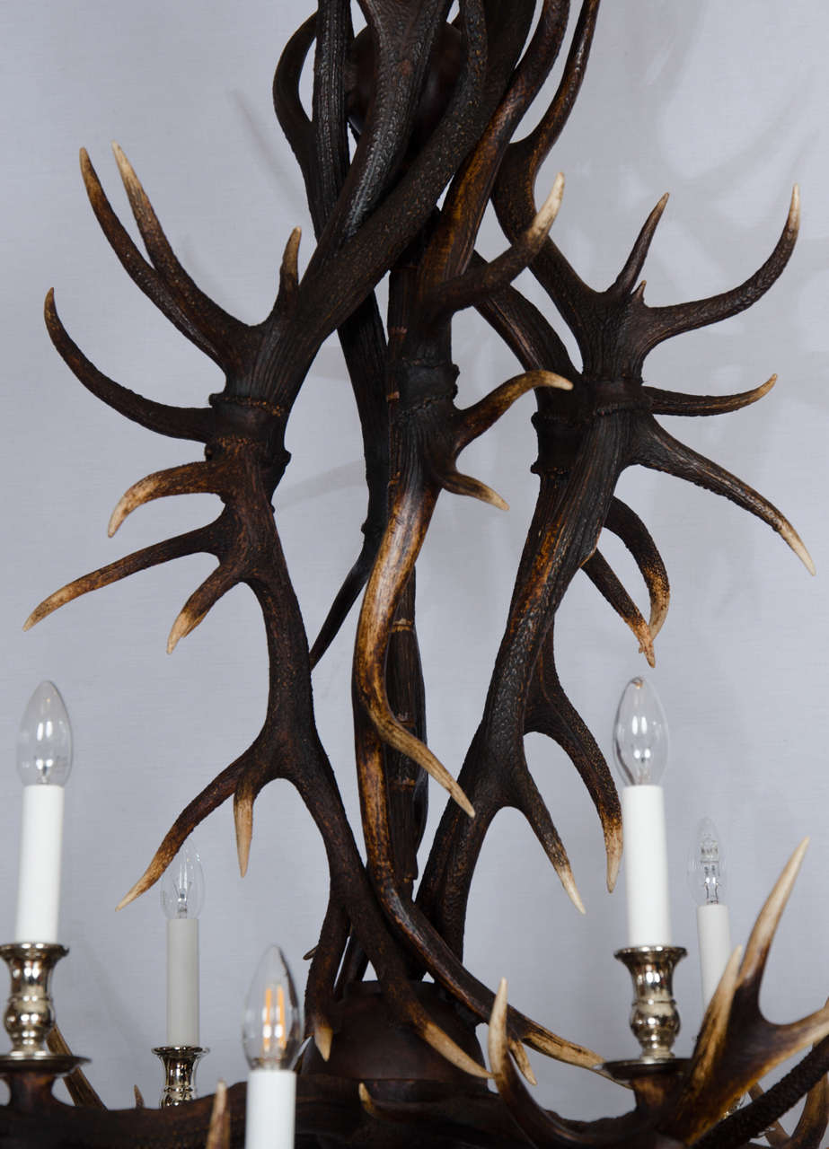 This outstanding antler chandelier was custom designed and made from naturally shed large red deer from Scotland. This unique light features two-tiers and 12 candle styled lights with brass hardware. The hardware can also be done in nickel plate, if