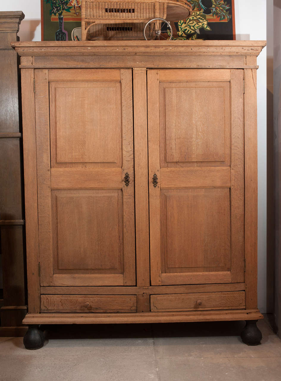 Early 19th century simple Baroque styled armoire in white oak. Bare finish except for ball feet which are in original ebonized black.
Armoire has been professionally and sensitively restored.
Double throw original key closure
inside depth 20 1/2
