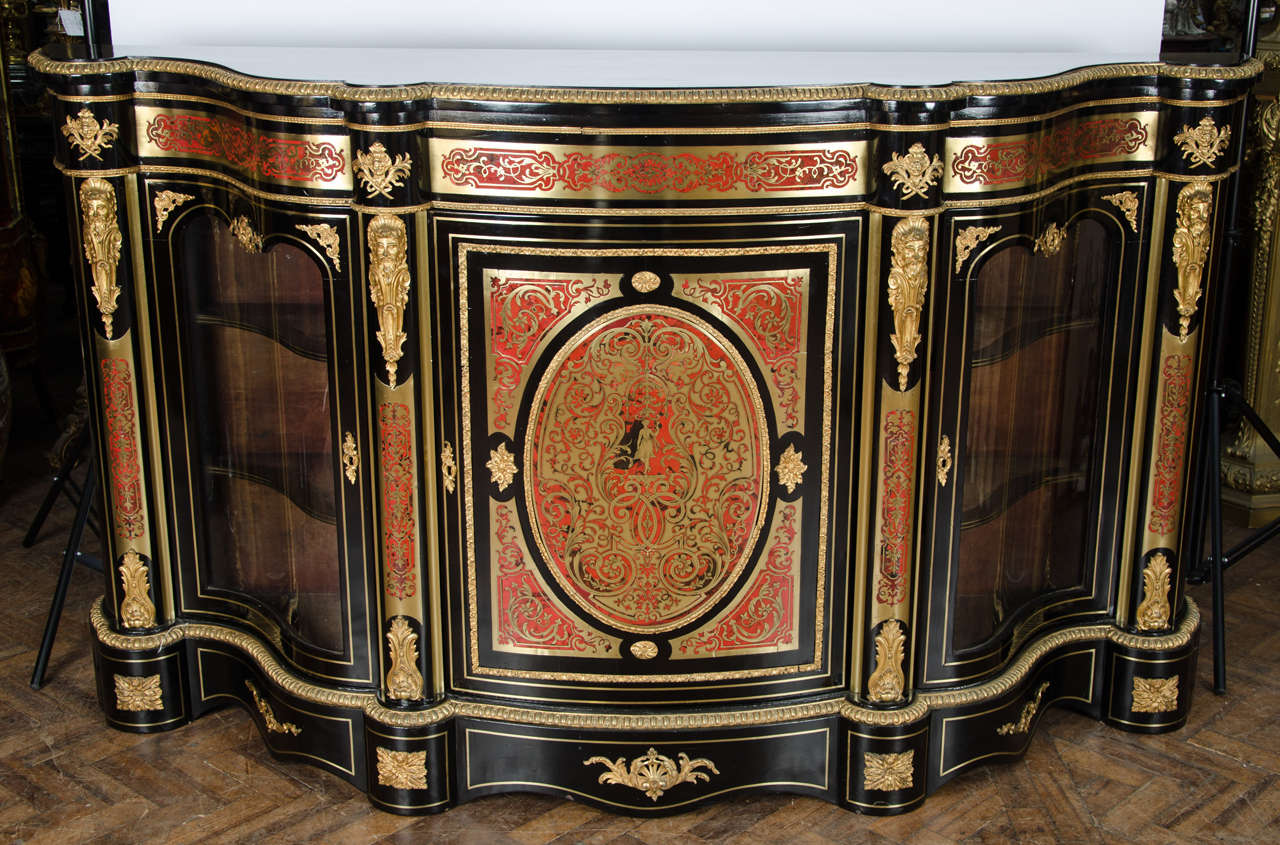 A very impressive large French Boulle inlaid serpentine fronted credenza, having ormolu mounts, shaped glazed doors to either side of the inlaid panelled central door and raised on a plinth base.