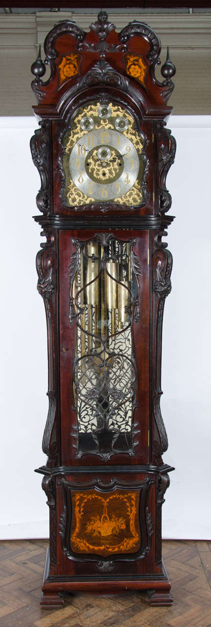 A very imposing Chippendale influenced mahogany longcase clock with carved scrolling decoration to the case, satinwood inlay and carved fretwork to the door. The eight day three train arch dialed movement has strike/ silent and a Westminster and
