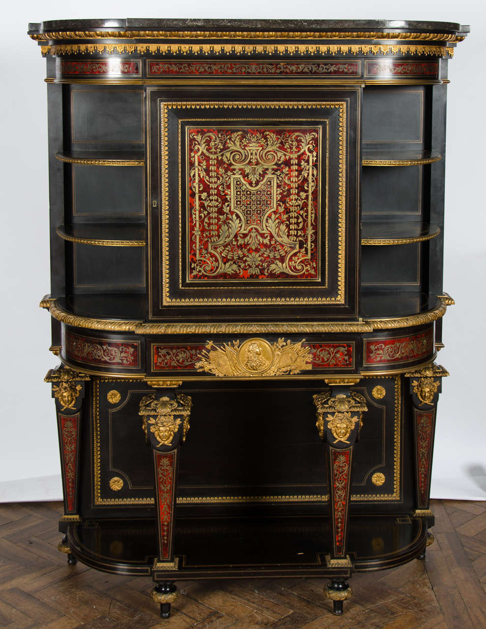 A fine quality French Louis XIV style Boulle inlaid bow fronted side cabinet, having a marble top, open shelves either side of the finely inlaid central door. A single frieze drawer with a gilded ormolu mount depicting the bust of Louis XIV. Raised