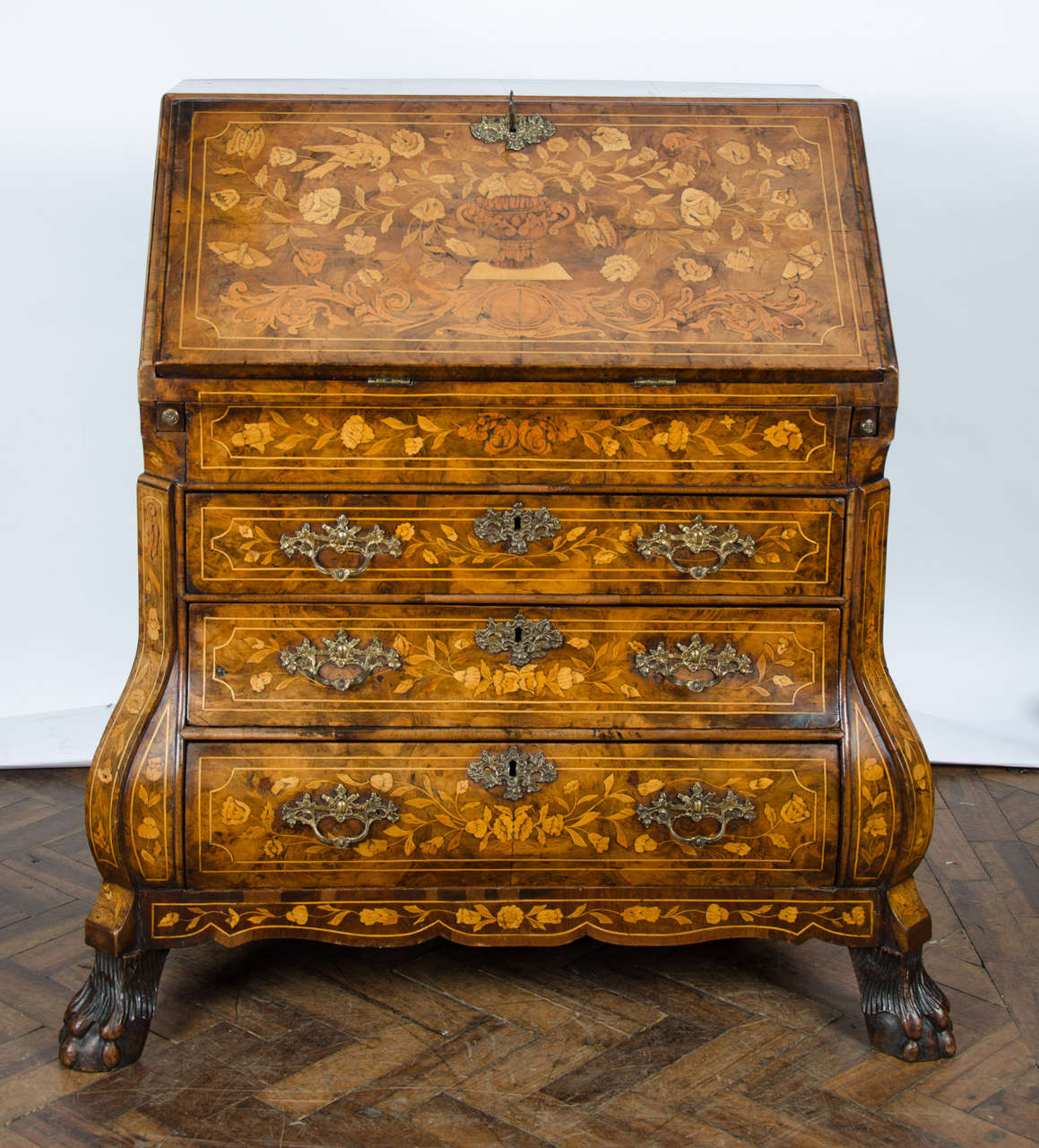 A very good quality 18th century Dutch marquetry bureau with floral inlaid decoration. The interior fitted with drawers, cupboards, and a well. The front being bombe fronted, having canted corners, the original brass handles and raised on ball and