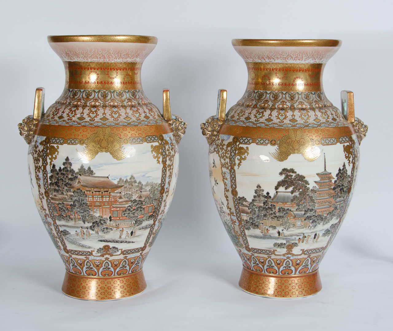 A fine quality large and impressive pair of Japanese Kutani vases, having Lion mask handles and scenes of women playing in the gardens.