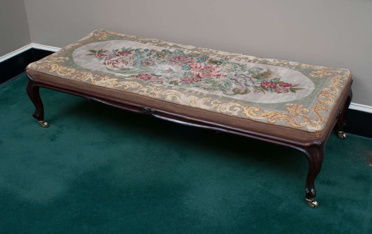 We don't know if the needlepoint upholstery on this bench is original, but it is certainly very old and beautiful, its worn condition gives the piece a patina and genuineness that cannot be copied. This sturdy bench is unusually wide and is