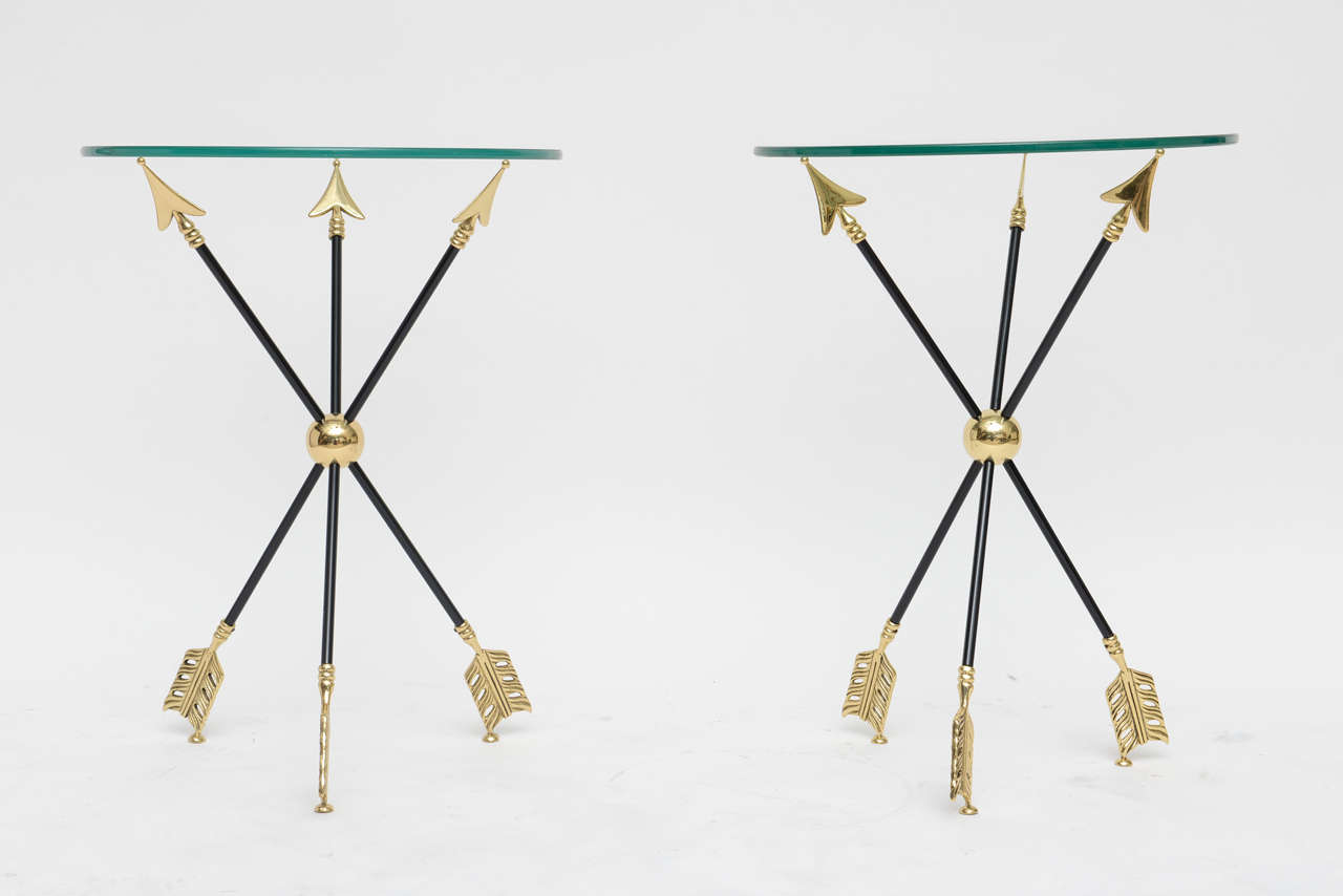 Beautifully restored Neoclassical side tables attributed to Maison Jansen. Solid brass arrows form a tripod base for half-inch glass tops. Professionally polished and lacquered.