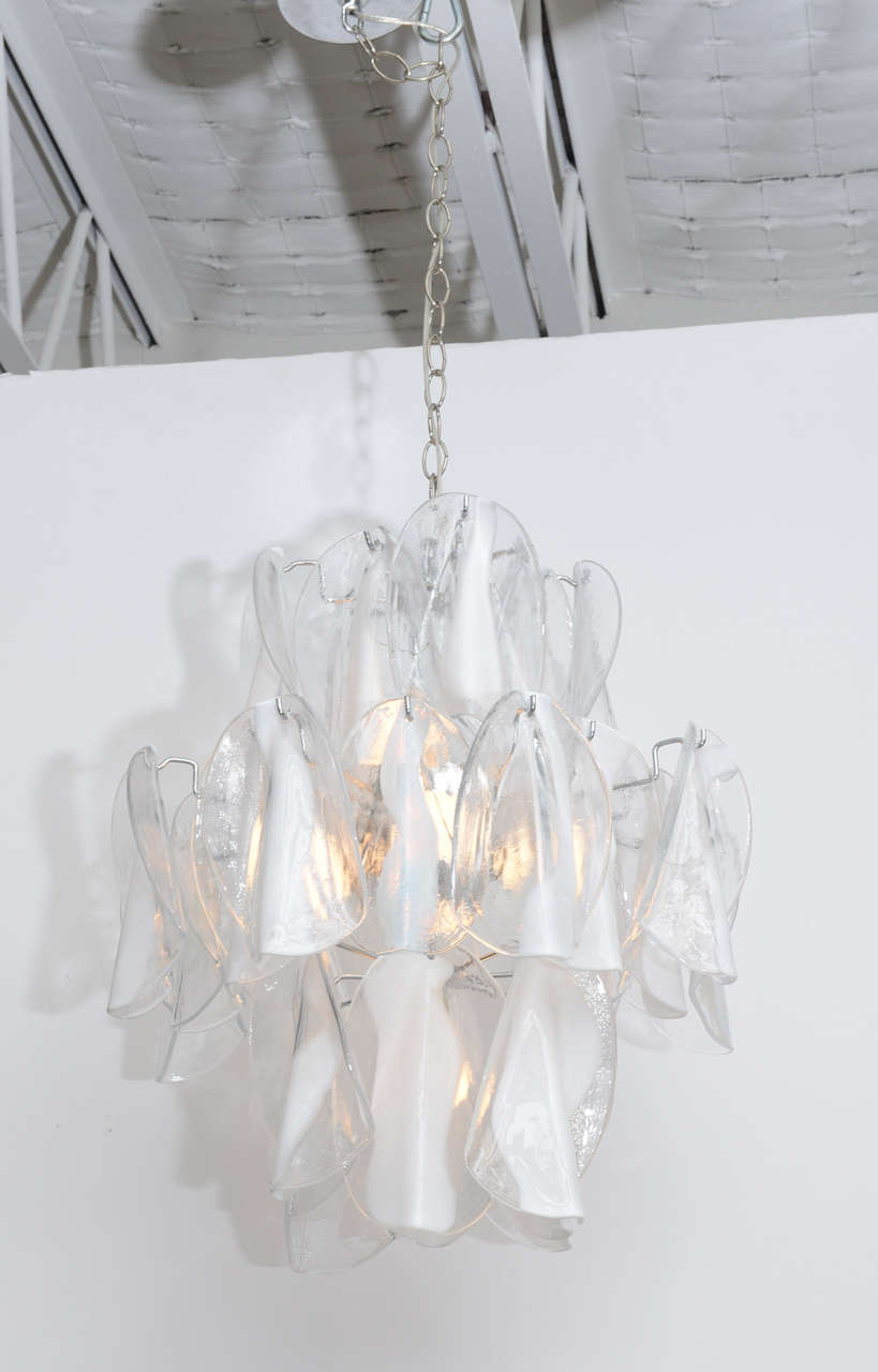 An eight-light, three-tiered Murano glass chandelier by Mazzega. Folded clear and white handblown glass pendants hang from a chromed metal frame. Cleaned, polished, and re-wired. Measurement below is for body of chandelier only. There is an