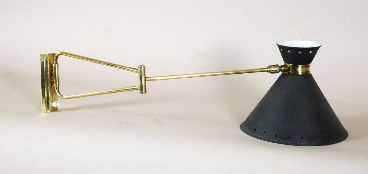 1950s wall sconce by Pierre Guariche with gilded brass articulated arm: star perforated tôle shade set on brass ball-bearing.  Wired for European use.