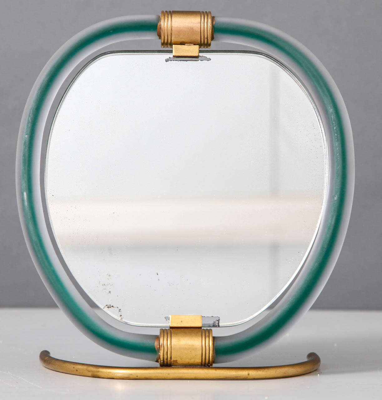 A very stylish vanity mirror, the wide circular border of hand-blown Murano glass, clear with green through and bronze detailing,geometric easel back.