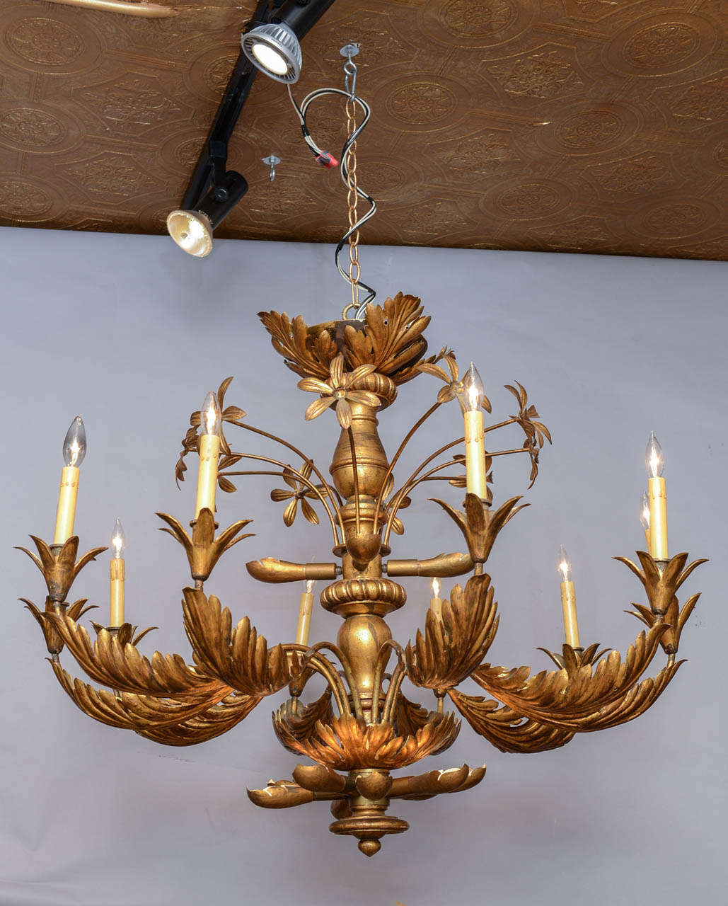 Fabulous chandelier, having turned giltwood center column with 10 scrolling gilded iron palm leaf candlearms, 10 long stemmed flowers and 12 pods concealing additional uplights.