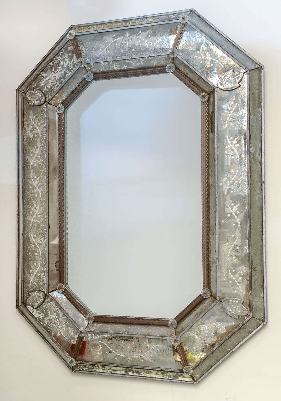 Venetian mirror, octagonal shape, its center outlined with glass rope connected by rosettes, each panel having scrolling eglomise and etched floral designs.