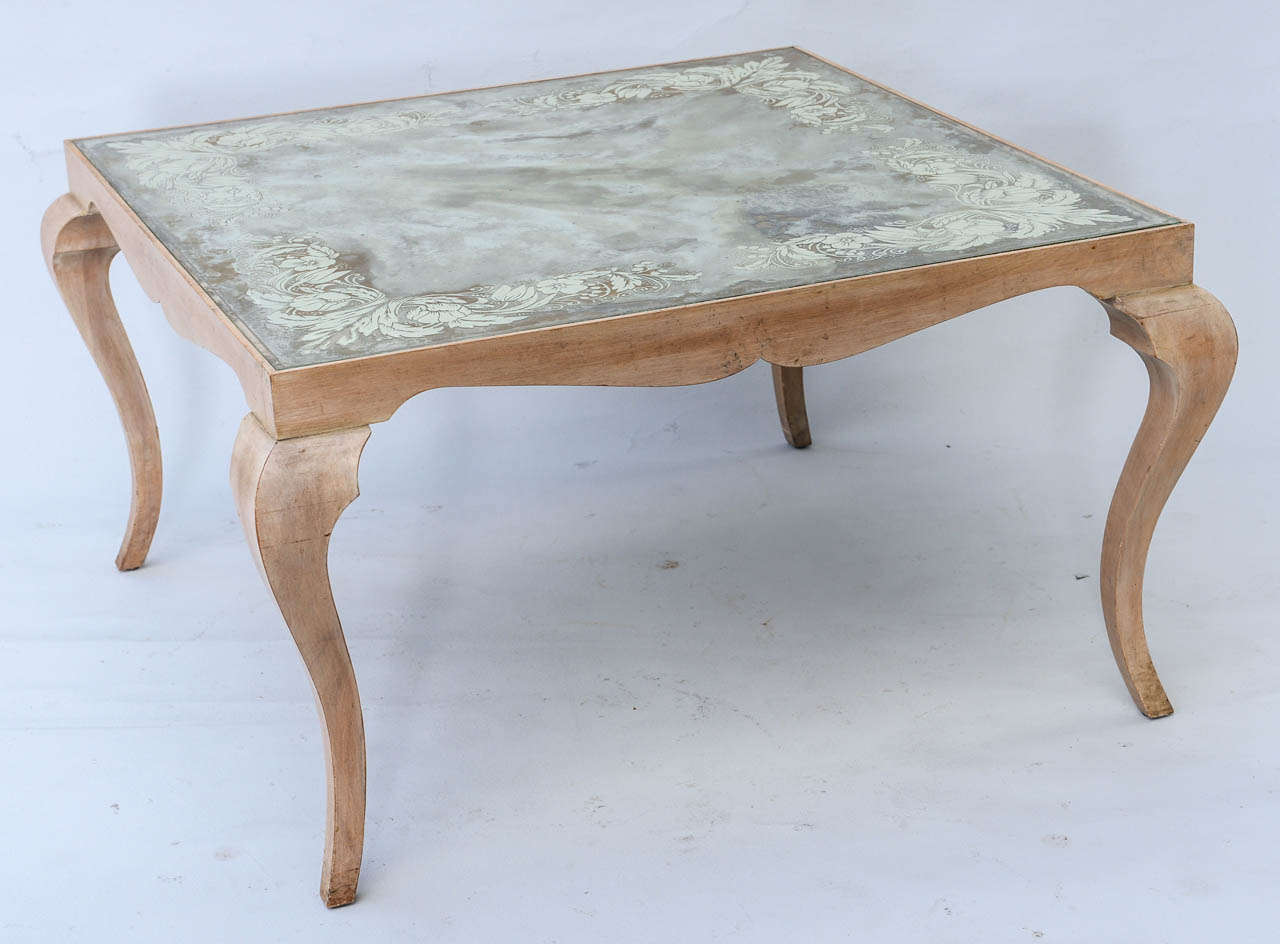 Coffee table, having eglomise (reverse painted) top with scrolling floral designs, raised on pickled wood stylized cabriole legs.