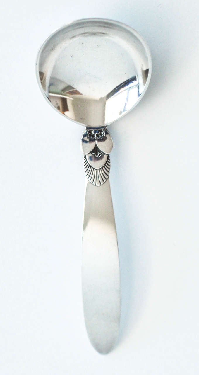 A small, vintage sterling silver serving spoon in the cactus pattern by Georg Jensen. First introduced in 1932 by Gundorph Albertus (1887-1970), the cactus pattern was inspired by the Art Deco movement and remains a popular Jensen design today.