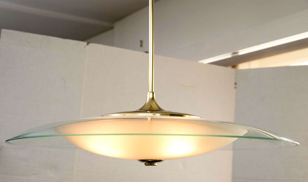 A hanging saucer form hanging pendant light. The larger top glass is clear with  green hued edge. The lower glass is a textured opaque white. The hardware is all solid brass. The original ceiling cap is included. All electrical wiring has been