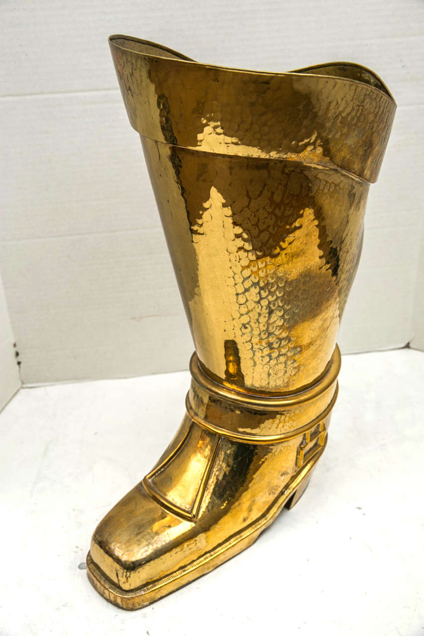A mid-20th century French hammered brass umbrella stand in the form of a horseman's boot.