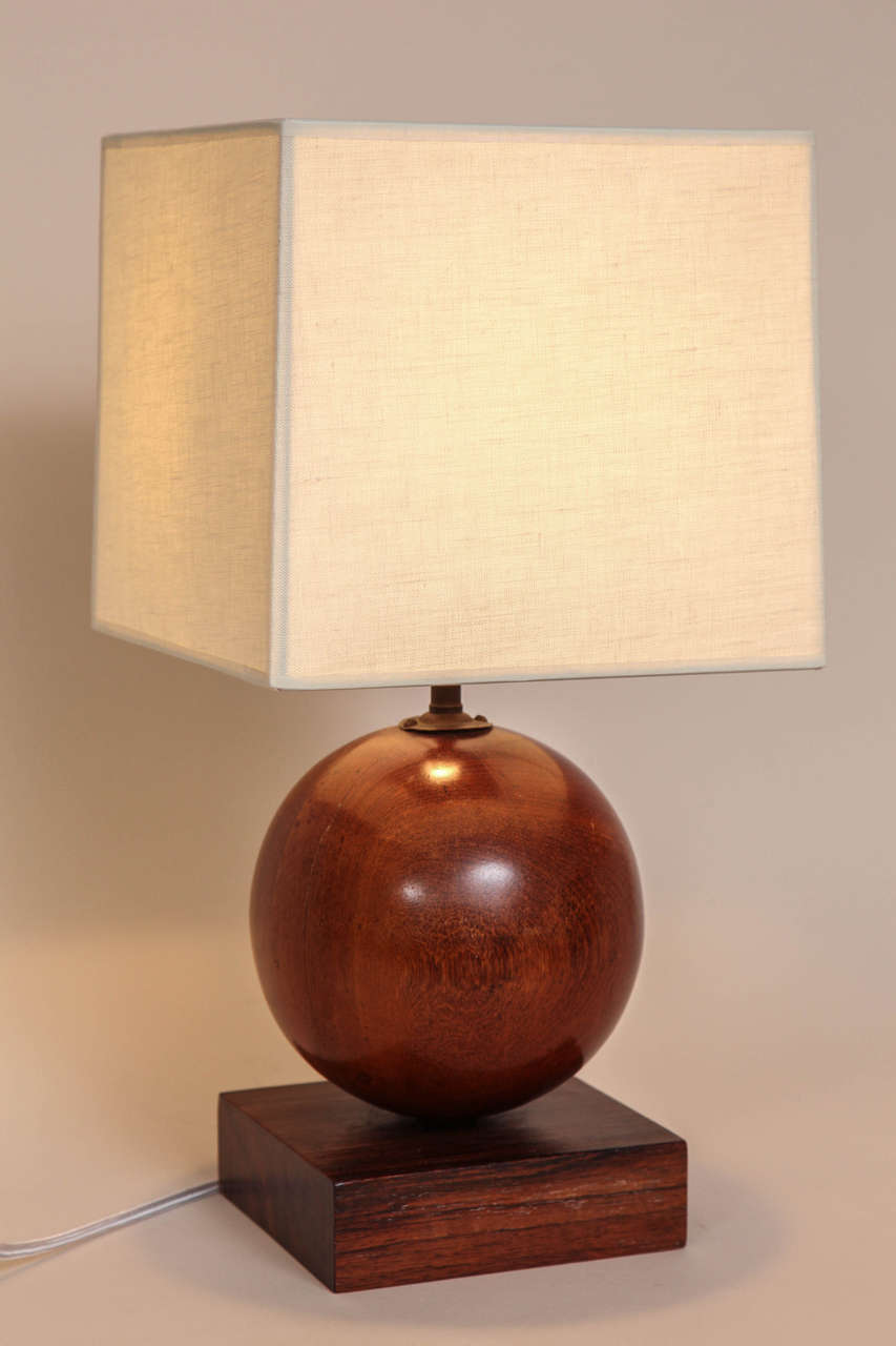 With a spherical rosewood body on a square rosewood base and with a linen shade. Has original French electrical components, but newly rewired to American standard and with dimmer switch.
17 3/8” high with shade; 11” high base; 6” square