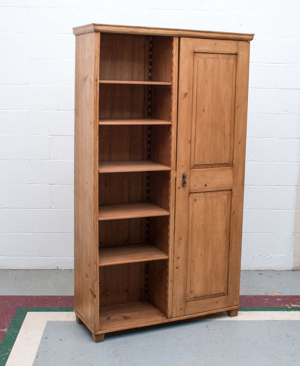 A wardrobe with an unusual configuration of a single raised panel door on one side and a run of five open shelves on the other. Both interior and open shelves are fully adjustable on original wooden track.