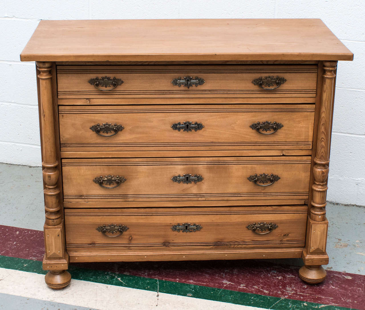 A handsome and compact pine chest of four beechwood fronted hand-cut dovetailed drawers flanked by turned columns.