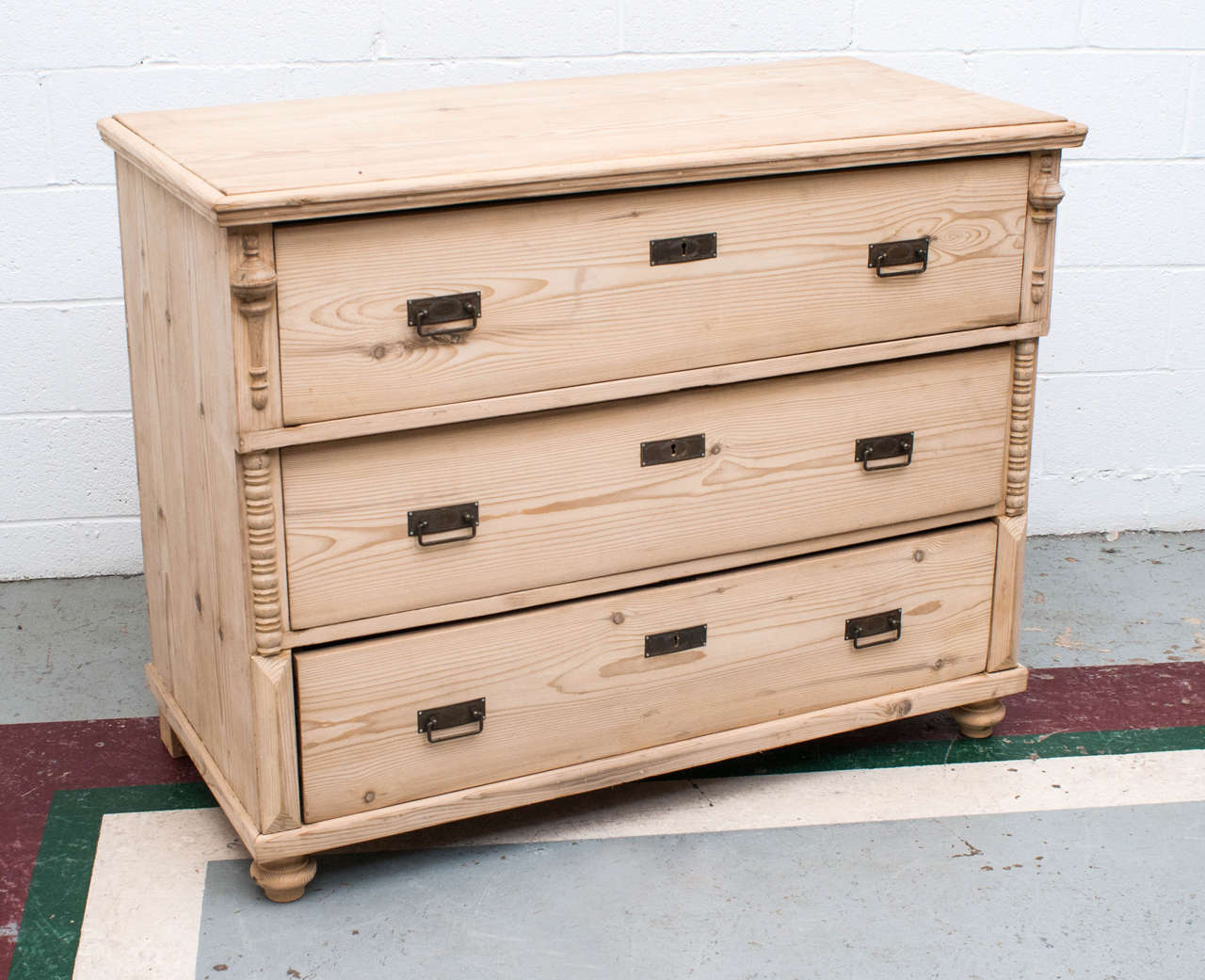 A large pine chest of three deep hand-cut dovetailed drawers. Applied split balusters and bobbin molding to the front sides. Shown in stripped pine.