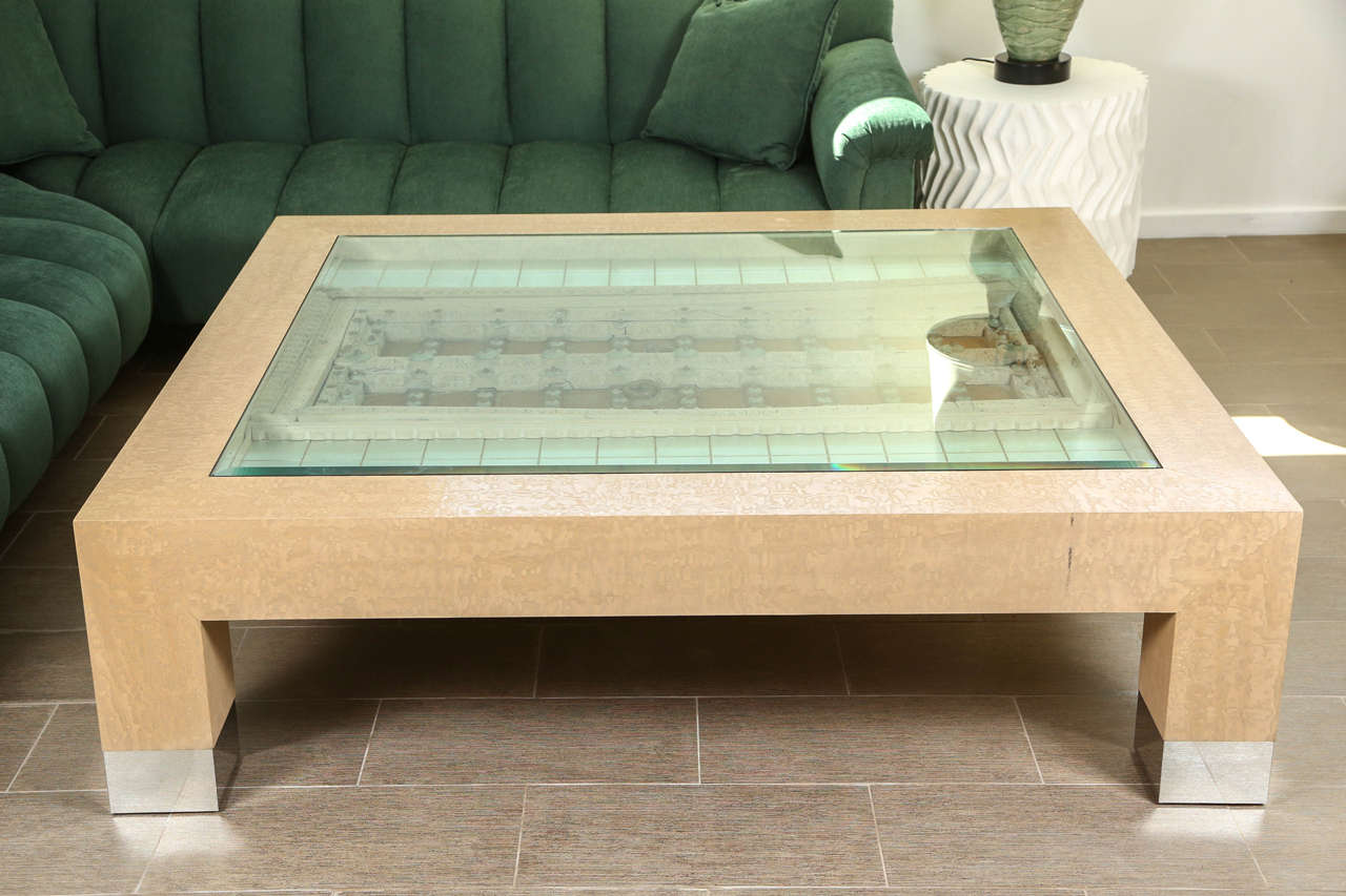 Wonderful large coffee table designed by Steve Chase.
This elegant wood coffee table with chrome capped trim features an antique wooden door which is inset and flanked by glazed silver leaf tiles and is covered by a glass top.