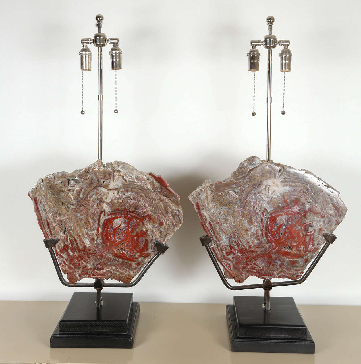 Pair of lamps made of spectacular matched and polished slabs of petrified wood mounted in metal frames on wooden bases. The lamps have been. Newly rewired with nickel-plated double clusters.