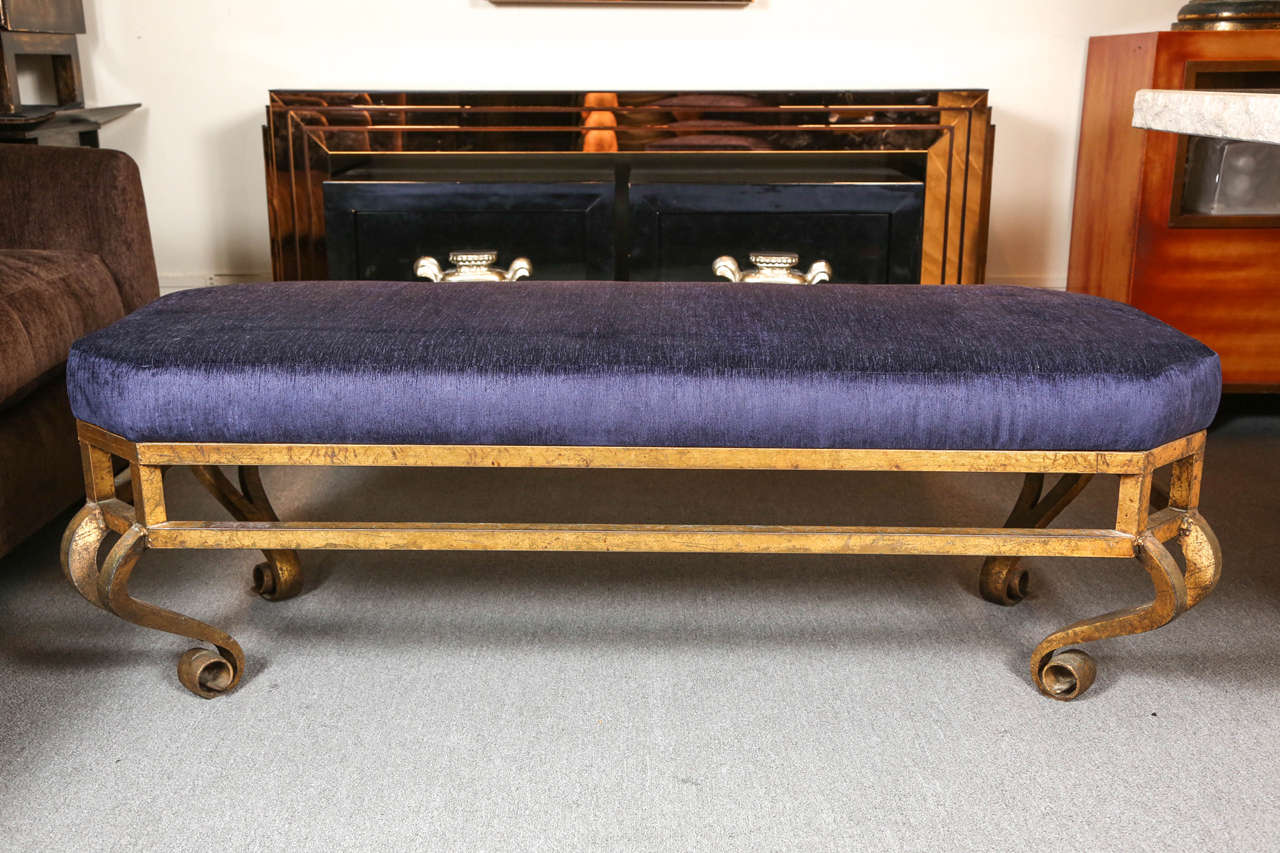 Elegant gilt leafed bench constructed of iron with a scroll detailed base.
The bench has been reupholstered in midnight blue chenille fabric which has a slight hint of purple.