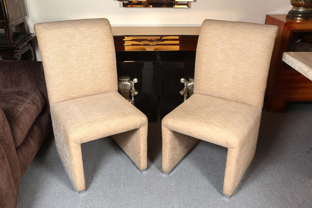 Set of four elegant chairs by Steve Chase.
The chairs are upholstered in a silk mix fabric and are finished around the bases with a chrome trim.