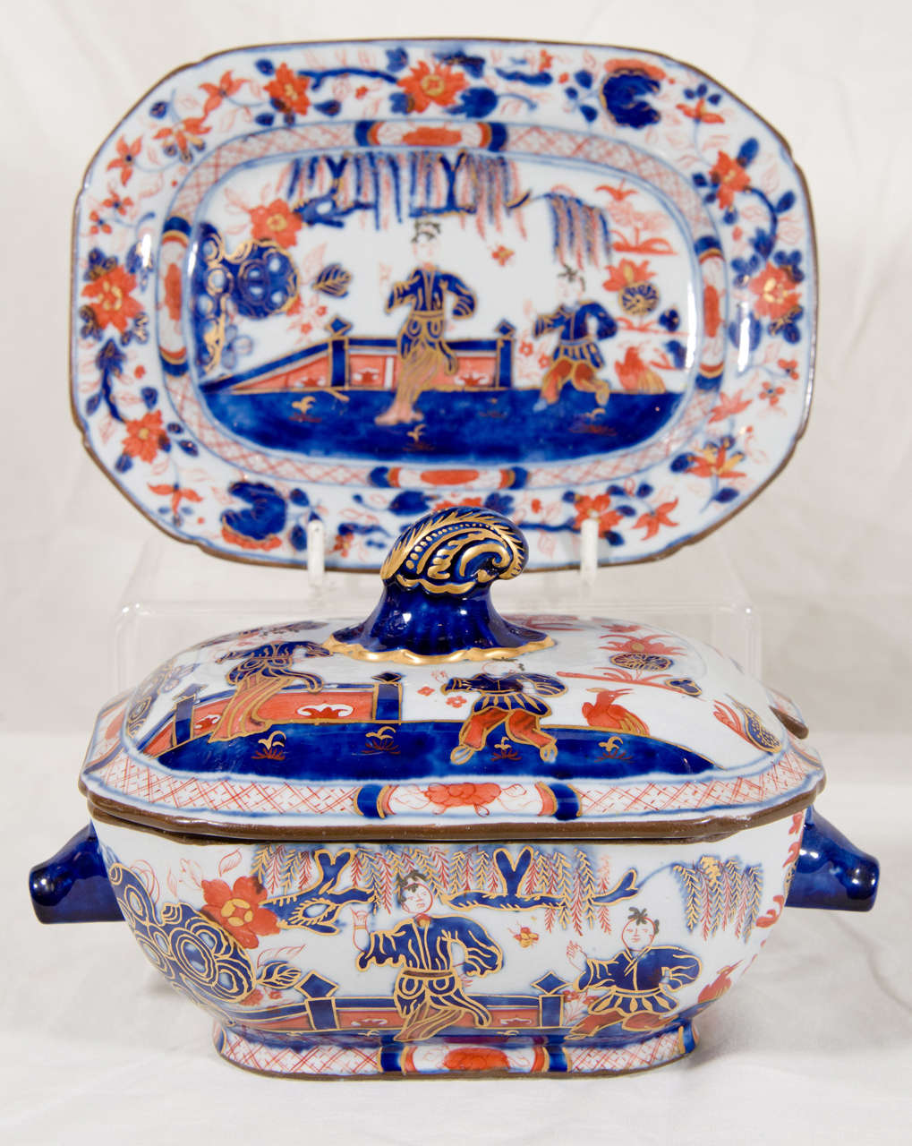 A pair of small tureens and stands decorated in an Imari inspired chinoiserie pattern showing two figures in a flowering garden. They were made by Turner, the inventor of ironstone, between 1795 and 1805. John Turner created and held the first