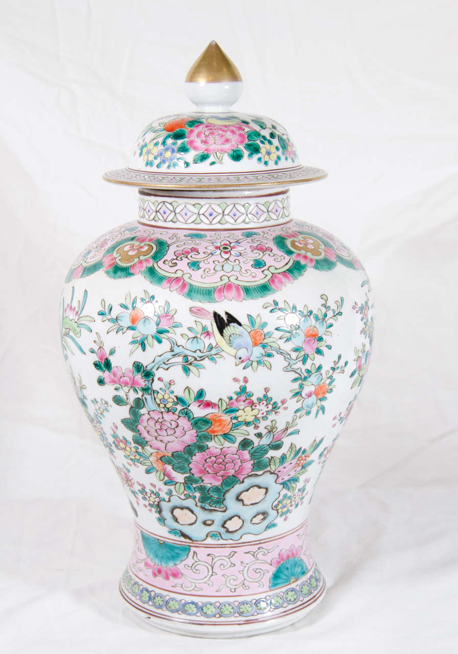 A Pair of Famille Rose ginger jars painted in pastel colored enamels. The vases are decorated with songbirds among a profusion of peonies and rockwork and on the reverse decorated with a traditional flower filled vase. Around the shoulders and base