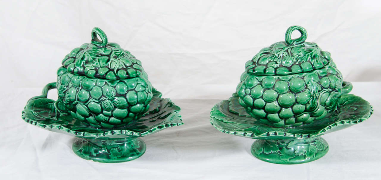 A pair of early 19th century green glazed Creamware sauce tureens molded in the form of a bunch of grapes with attached stands and stock finial. Green glazed earthenware objects were popular throughout Britain and the American colonies in the 18th