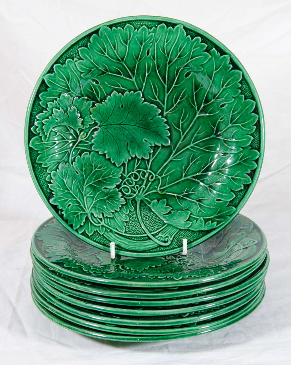 A set of eight 19th century English Majolica plates colored with a beautiful green glaze. The impressed design features a cluster of grape leaves.