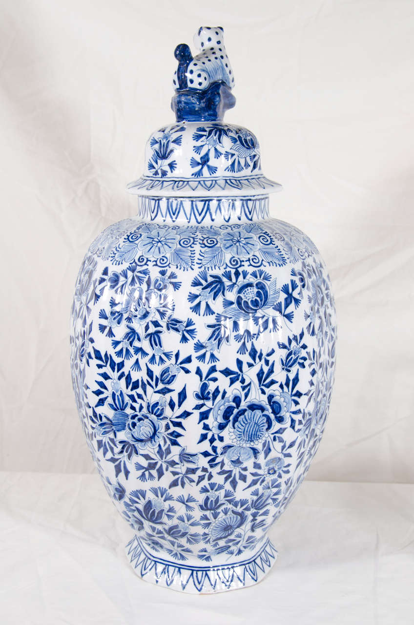 A pair of brightly painted blue and white Dutch delft vases with an all-over design of peonies, leaves and scrolling vines. The covers have traditional leopard finials.
The bottom of each vase with the mark of the 