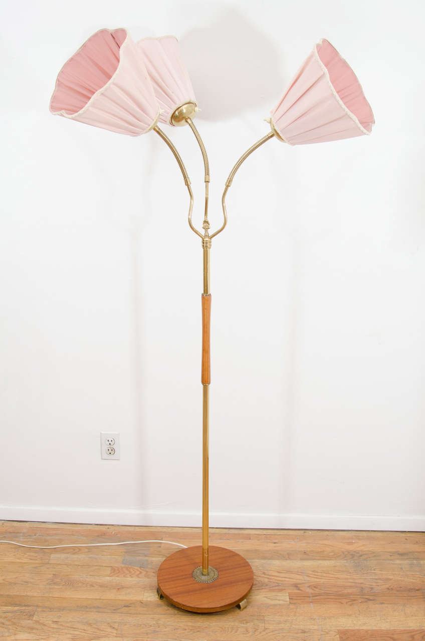 A whimsical design, with three flexible arms on a mahogany, birch and brass base, the pink 