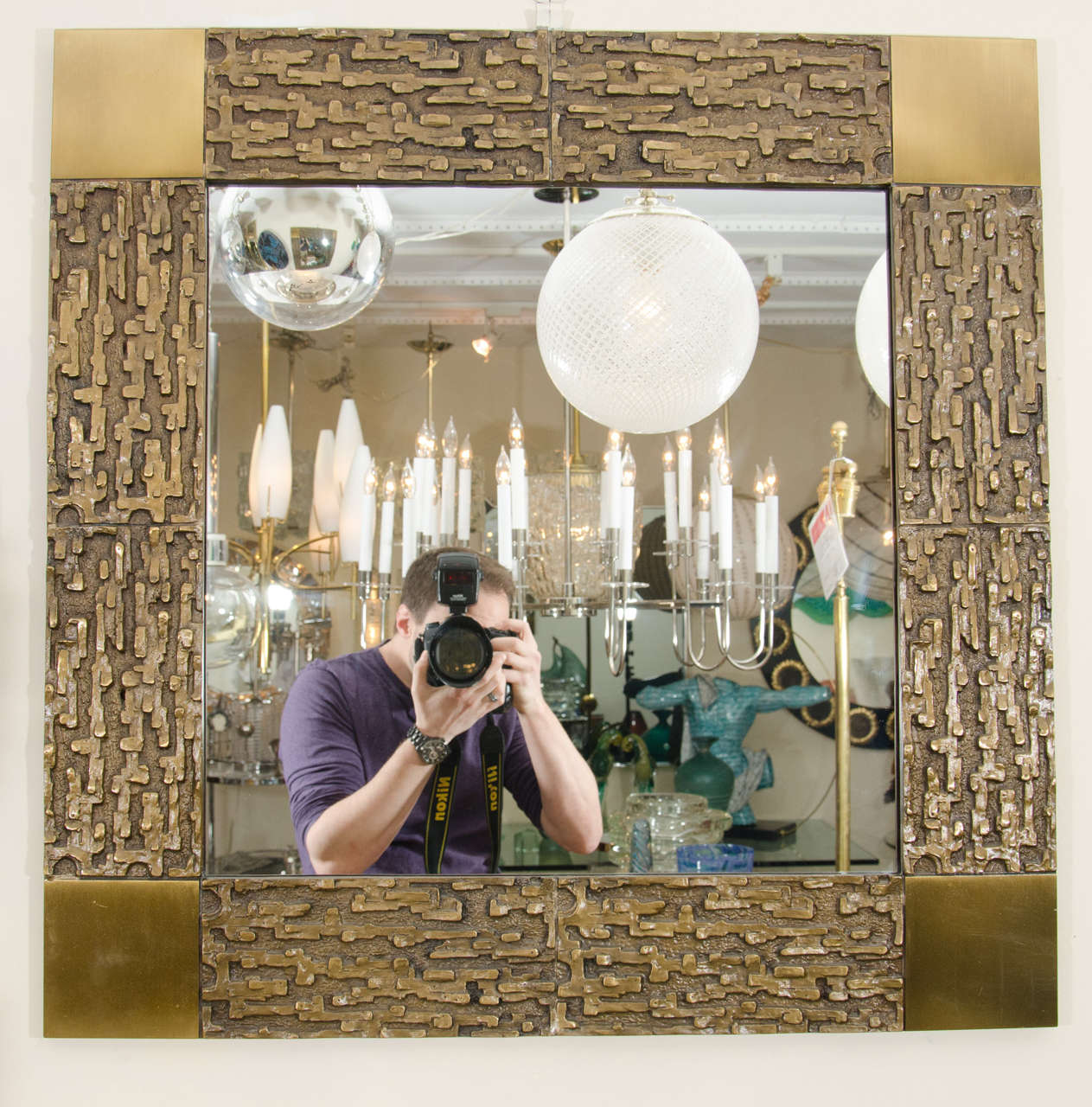 Square bronze mirror with relief surround and brass detail at corners by Luciano Frigerio.