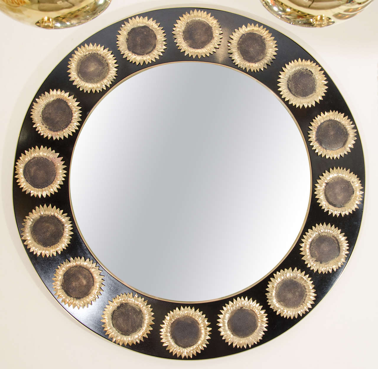 Circular mirror with lacquered and ebonized wood surround featuring brass and enameled sunflower details.