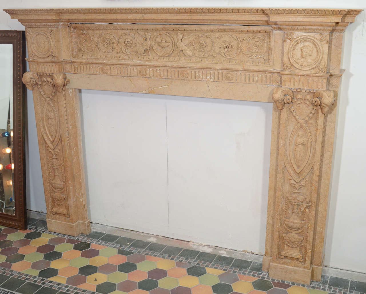 This highly detailed English sienna carved marble mantel with rams head detail was reclaimed from the Vanderbilt mansion on Sutton Place. It is unusual for an English mantel, because the center plaque is carved out of a block, as opposed to being