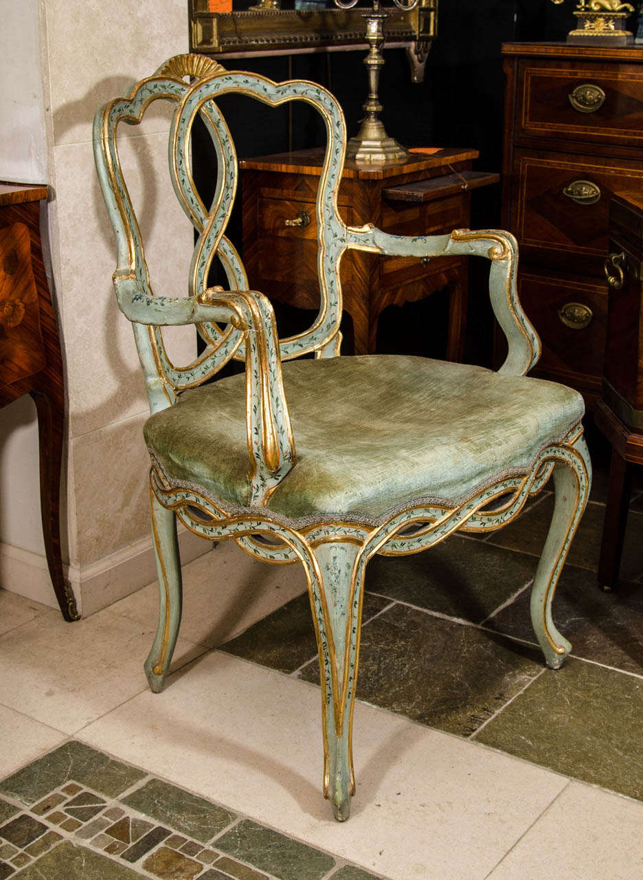 A pair of Venetian painted, stenciled and gilded carved fauteuils.